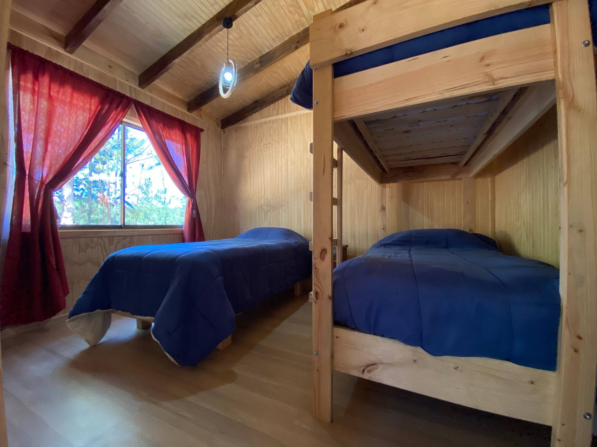 Segunda habitación con litera y cama individual, con ventana al bosque